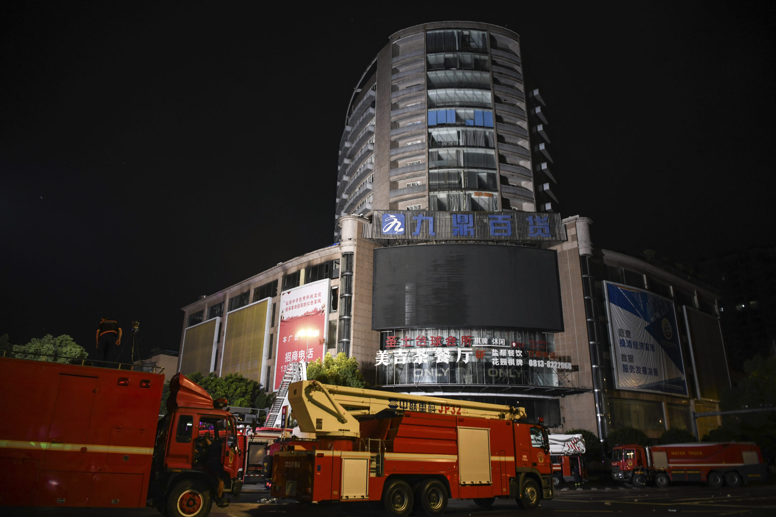 Fire engines are parked near a department store in Zigong City, southwest China's Sichuan Province on Thursday, following Wednesday's deadly fire at the department store.