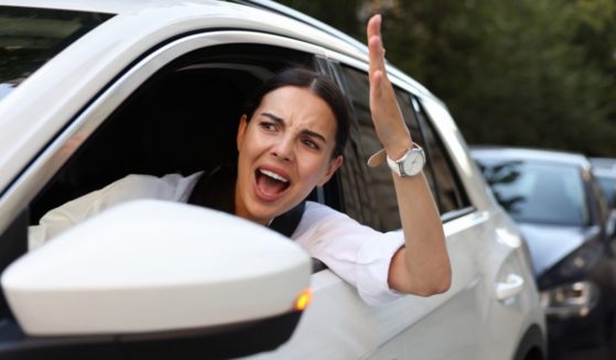 This image shows an angry female driver screaming at someone in a traffic jam.