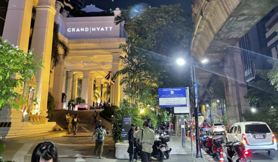 People walk outside a hotel where a number of people were found dead in Bangkok on Tuesday.