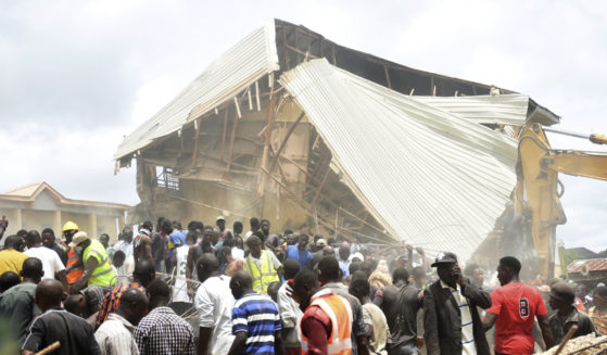 People and rescuers gather at the scene of a collapsed two-storey building Jos, Nigeria, Friday, July 12, 2024. At least 12 students have been killed after a school building collapsed and trapped them in northern Nigeria, authorities said on Friday.
