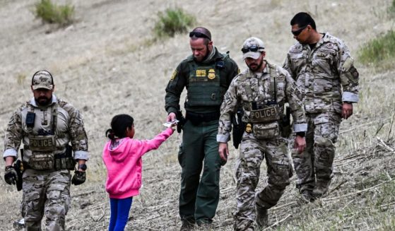 A US Customs and Border Protection officer gives food to an immigrant child waiting to be processed at a US Border Patrol transit center after crossing the border from Mexico at Eagle Pass, Texas on December 22, 2023.