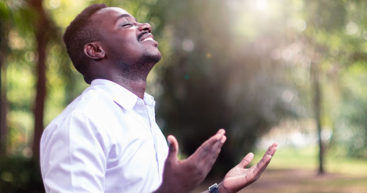 This image shows a man with his face toward heaven, eyes closed, and hands raised in worship of God.