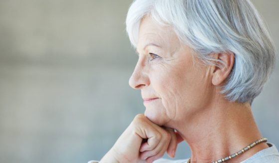 This image shows an older woman staring into the distance in a very thoughtful way.