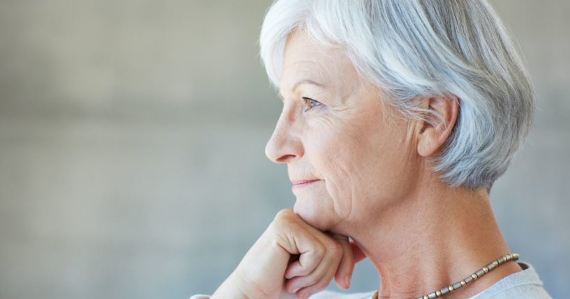 This image shows an older woman staring into the distance in a very thoughtful way.