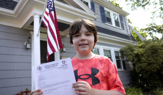 Danny Doherty, 12, of Norwood, Massachusetts, stands for a photograph Wednesday, August 21, 2024, in front of his home in Norwood, while holding a letter from the Town of Norwood Board of Health advising his family that they may not sell homemade ice cream at an ice cream stand near their home.