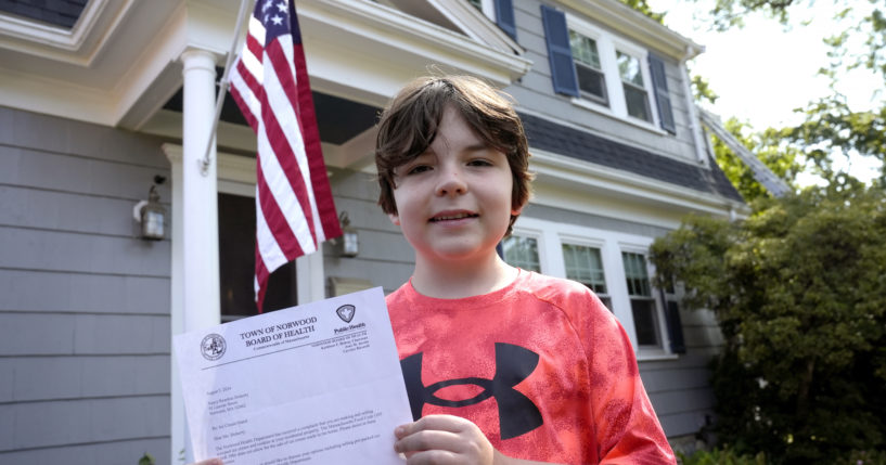 Danny Doherty, 12, of Norwood, Massachusetts, stands for a photograph Wednesday, August 21, 2024, in front of his home in Norwood, while holding a letter from the Town of Norwood Board of Health advising his family that they may not sell homemade ice cream at an ice cream stand near their home.