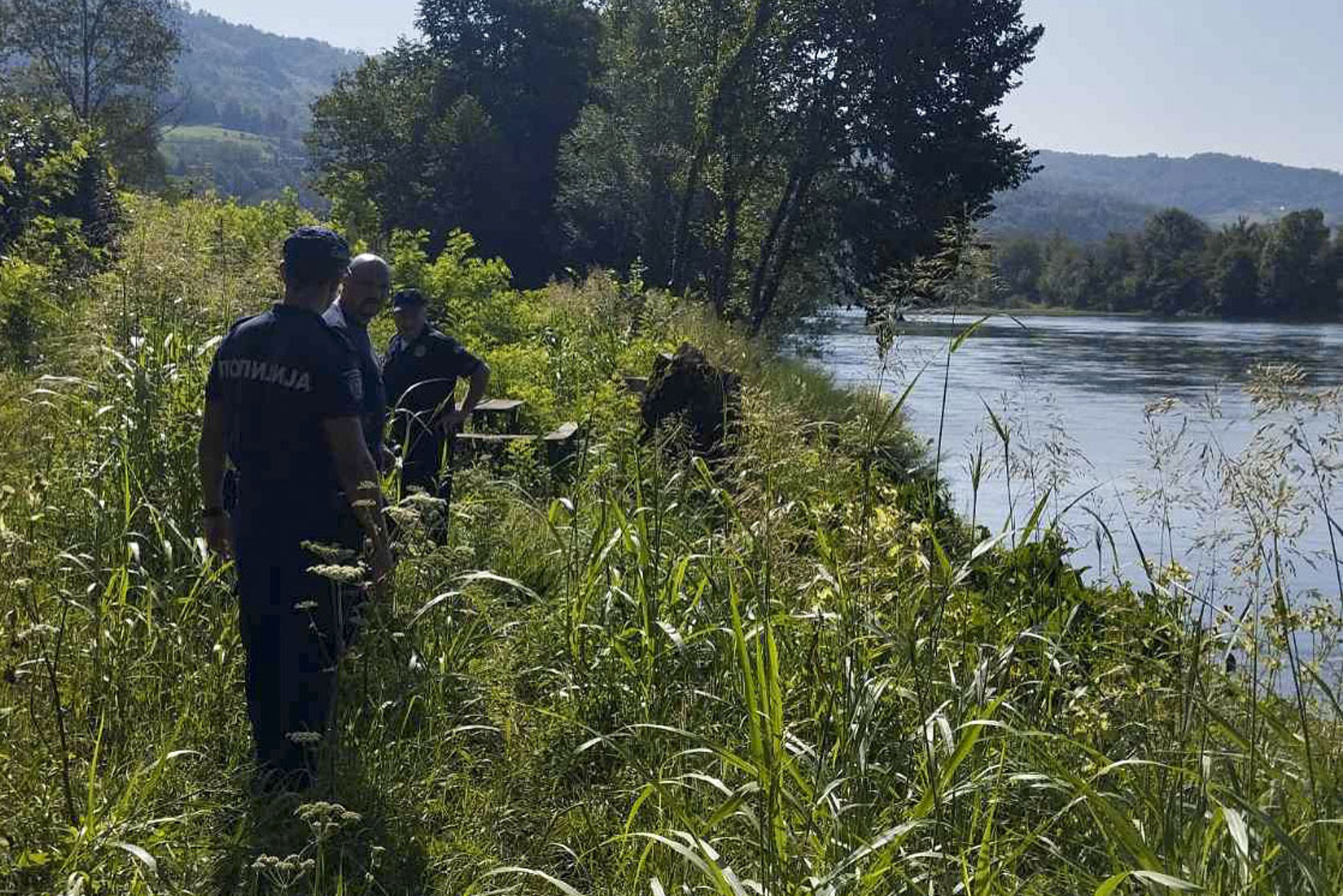 In this photograph made available by the Serbian Ministry of Interior, Serbian Police officers search a bank of the Drina River near the town of Ljubovija, Serbia on Thursday.