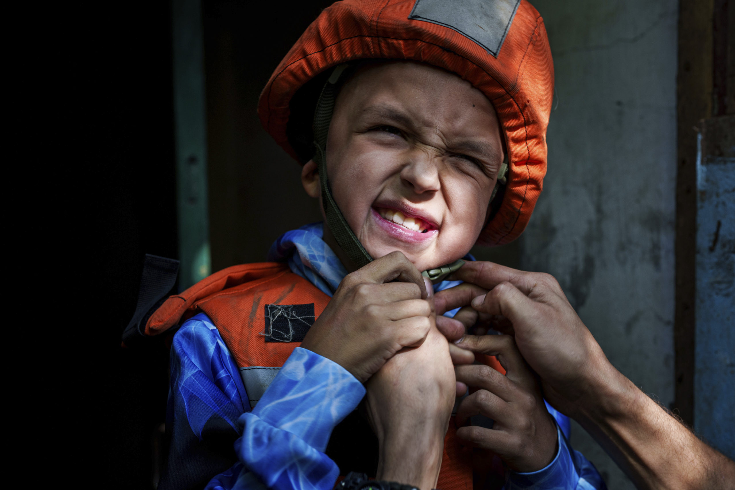 A Fenix team rescue worker places a helmet on Bohdan Scherbyna, 9, as he is evacuated with his mother Maryna Scherbyna and 14 year old sister Angelina Scherbyna, as local people as moved from Selidove to safe areas, in Pokrovsk, Donetsk region, Ukraine, on Tuesday.