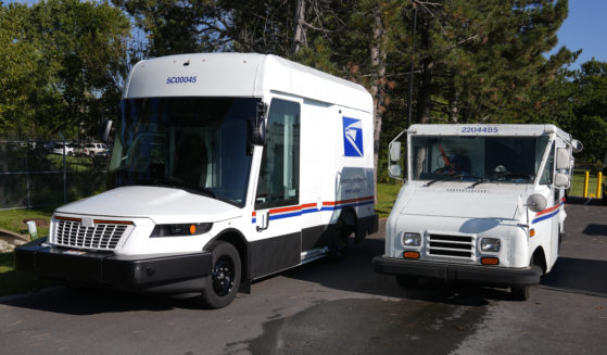 The U.S. Postal Service's next-generation delivery vehicle, left, is displayed as one of the current delivery trucks leaves the Kokomo Sorting and Delivery Center in Kokomo, Indiana on Thursday.