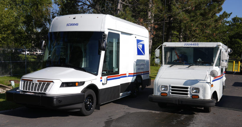 The U.S. Postal Service's next-generation delivery vehicle, left, is displayed as one of the current delivery trucks leaves the Kokomo Sorting and Delivery Center in Kokomo, Indiana on Thursday.