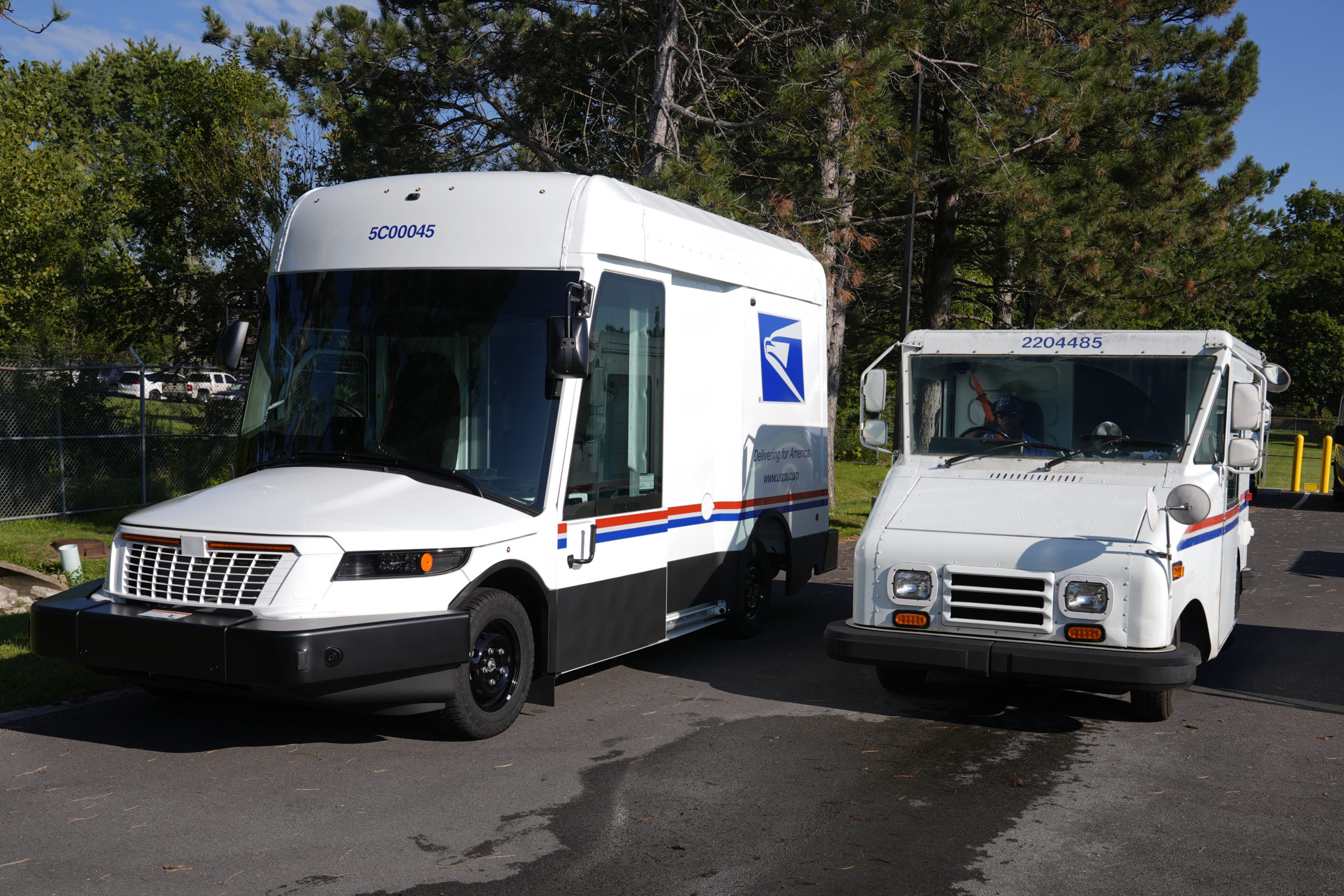 The U.S. Postal Service's next-generation delivery vehicle, left, is displayed as one of the current delivery trucks leaves the Kokomo Sorting and Delivery Center in Kokomo, Indiana on Thursday.