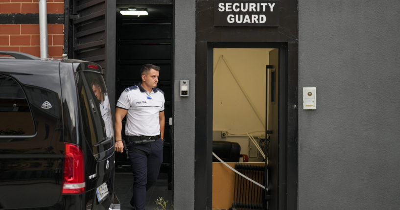 A police officer exits the residence of social media personality Andrew Tate during an early morning search raid, on the outskirts of Bucharest, Romania on Wednesday.