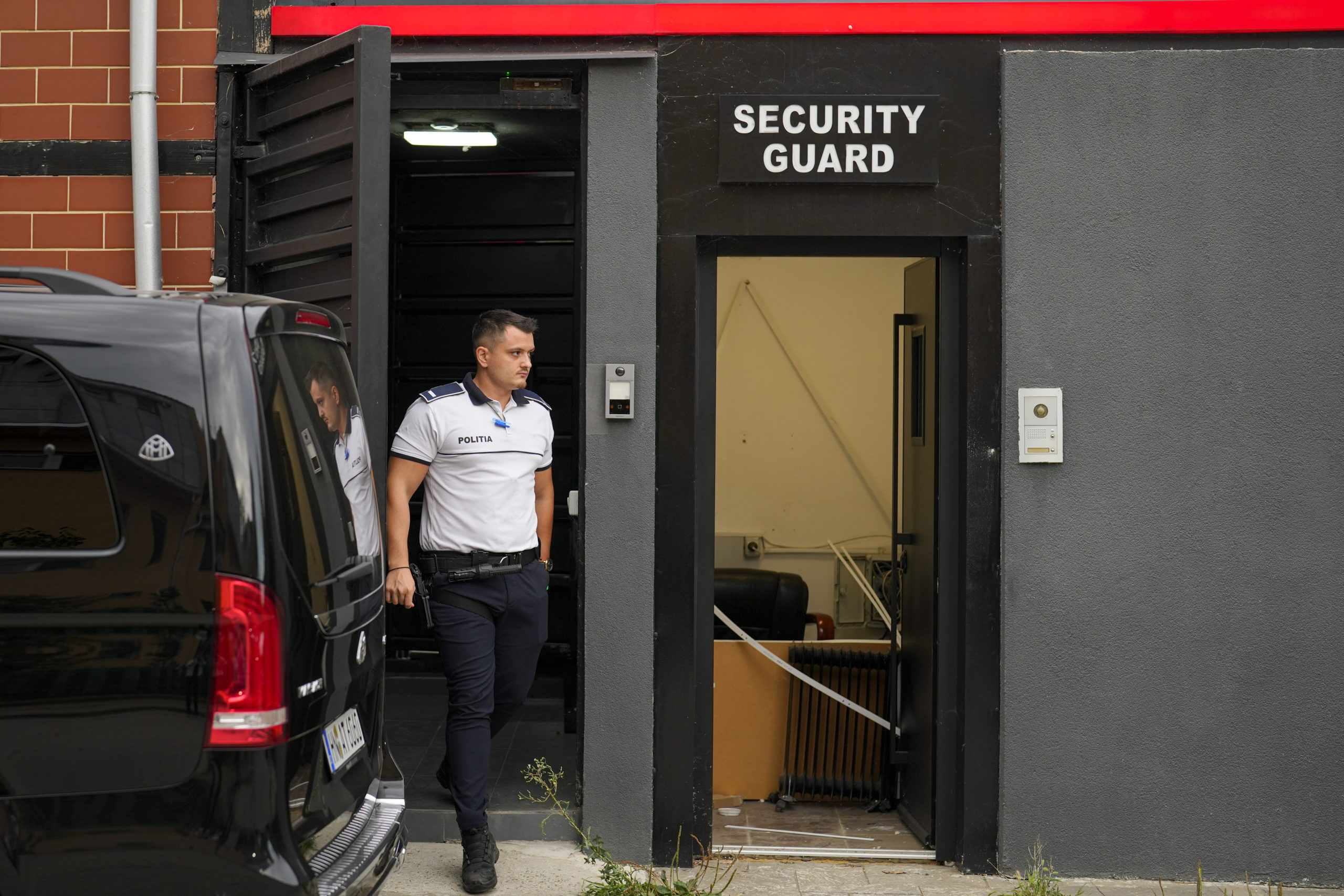 A police officer exits the residence of social media personality Andrew Tate during an early morning search raid, on the outskirts of Bucharest, Romania on Wednesday.