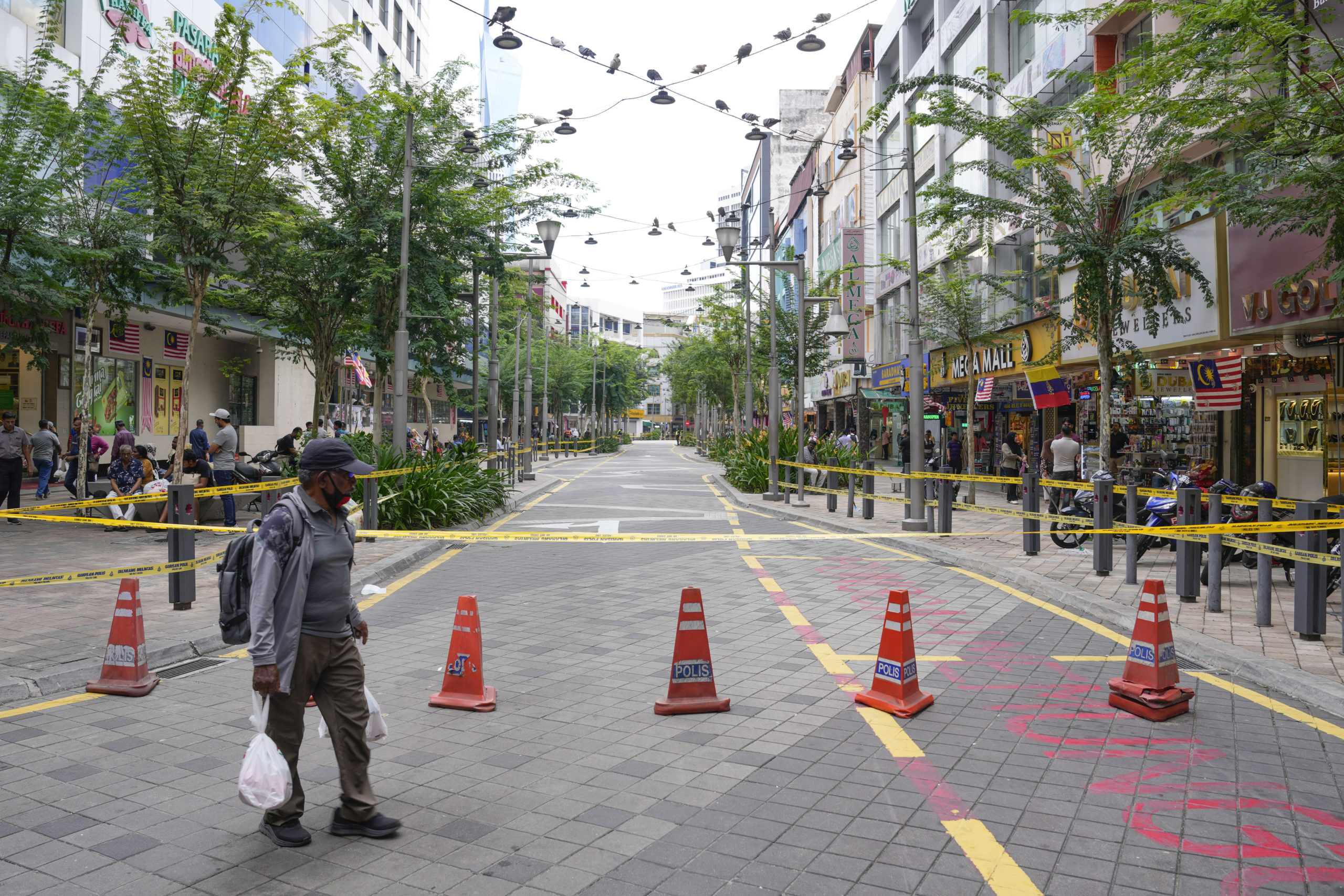 A man crosses a closed roadside after another deep sinkhole appeared a week after a woman fell into a sinkhole when a sidewalk caved in in Kuala Lumpur, Thursday, August 29, 2024.