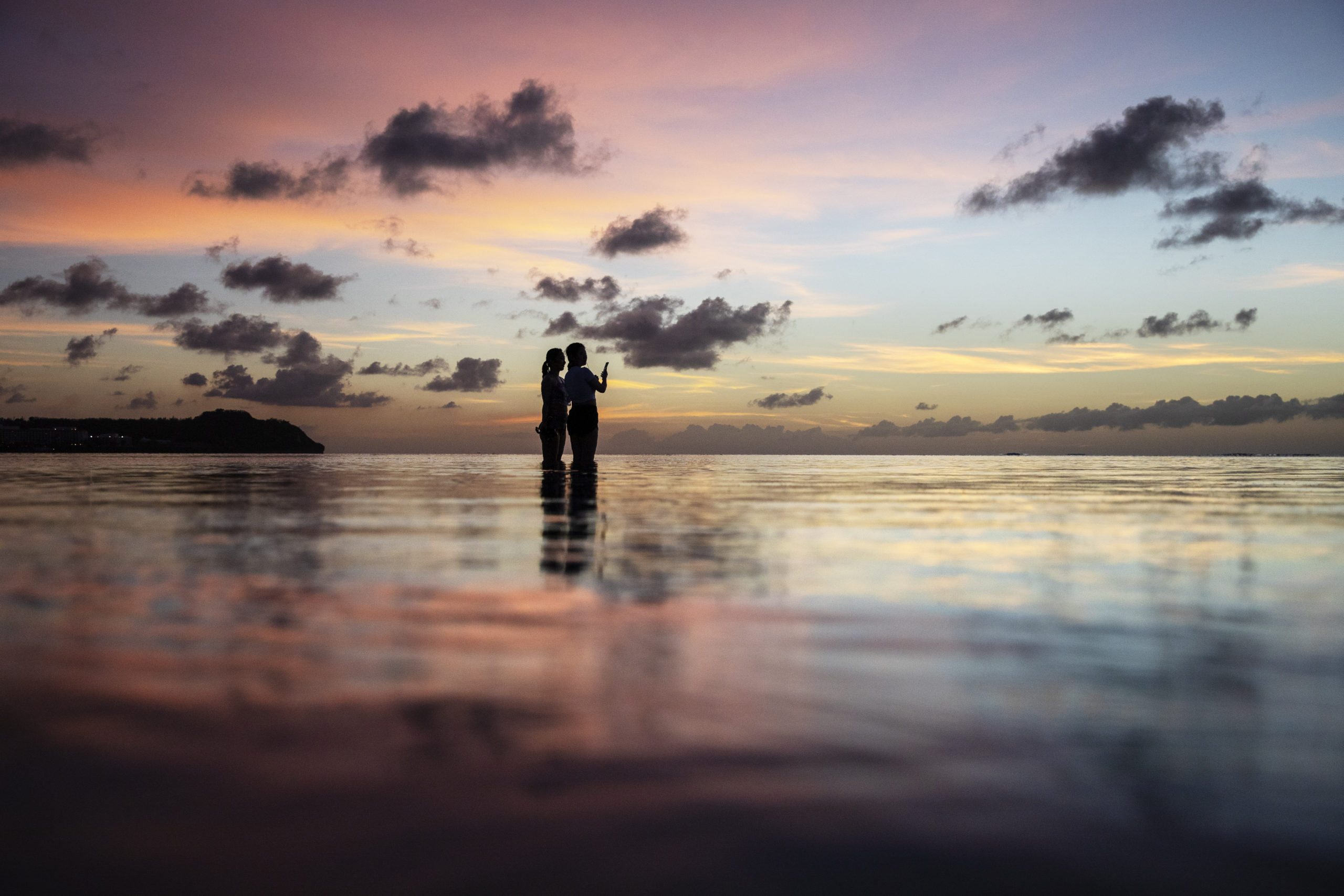 Tourists watch the sun set along a popular beach in Tamuning, Guam, May 6, 2019.