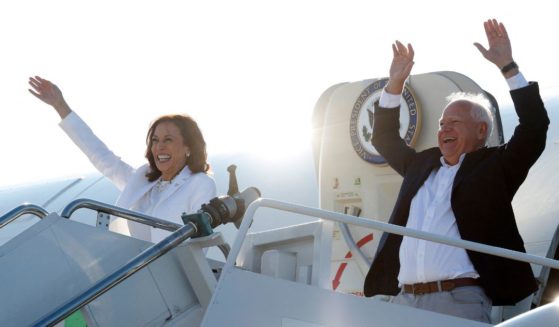 Vice President and 2024 Democratic presidential candidate Kamala Harris and her running mate Minnesota Gov. Tim Walz wave as they disembark Air Force Two for a campaign rally in Romulus, Michigan, Wednesday.