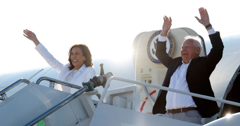 Vice President and 2024 Democratic presidential candidate Kamala Harris and her running mate Minnesota Gov. Tim Walz wave as they disembark Air Force Two for a campaign rally in Romulus, Michigan, Wednesday.