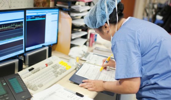 This stock image shows a nurse preparing medical paperwork in a hospital.