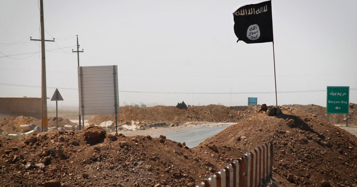 A flag of the Islamic State is seen on the other side of a bridge at the frontline of fighting between Kurdish Peshmerga fighters and Islamist militants in Rashad, Iraq, on Sept. 11, 2014.