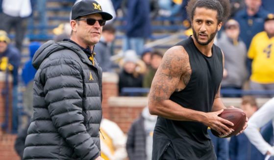 Colin Kaepernick, right, interacts with then-Michigan Wolverine head coach Jim Harbaugh. left, during a throwing exhibition at half time of the Michigan spring football game in Ann Arbor, Michigan, on April 2, 2022.