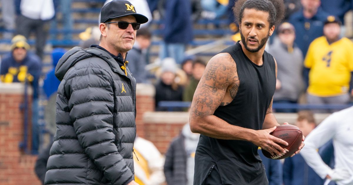 Colin Kaepernick, right, interacts with then-Michigan Wolverine head coach Jim Harbaugh. left, during a throwing exhibition at half time of the Michigan spring football game in Ann Arbor, Michigan, on April 2, 2022.