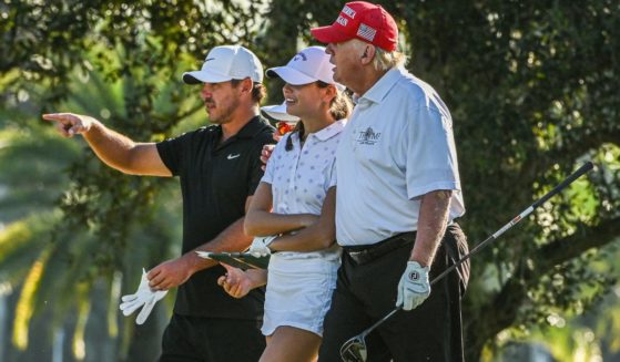 President Donald Trump, right, U.S. golfer Brooks Koepka, left, and Trump's granddaughter Kai Trump, center, play golf at Trump National Doral Miami golf club in Miami, Florida, on Oct. 27, 2022.