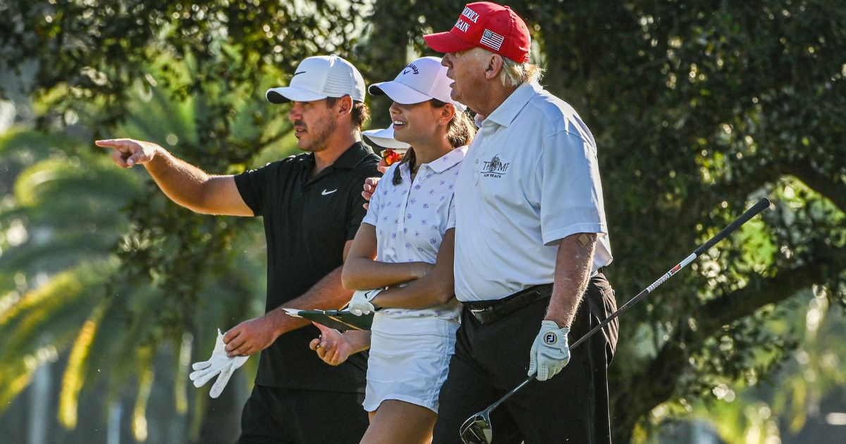 President Donald Trump, right, U.S. golfer Brooks Koepka, left, and Trump's granddaughter Kai Trump, center, play golf at Trump National Doral Miami golf club in Miami, Florida, on Oct. 27, 2022.