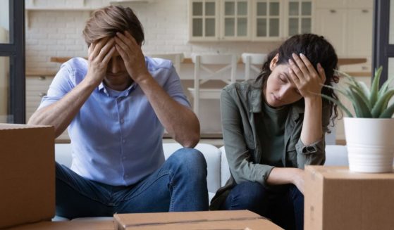 An exhausted young couple sits on a couch in this stock photo.