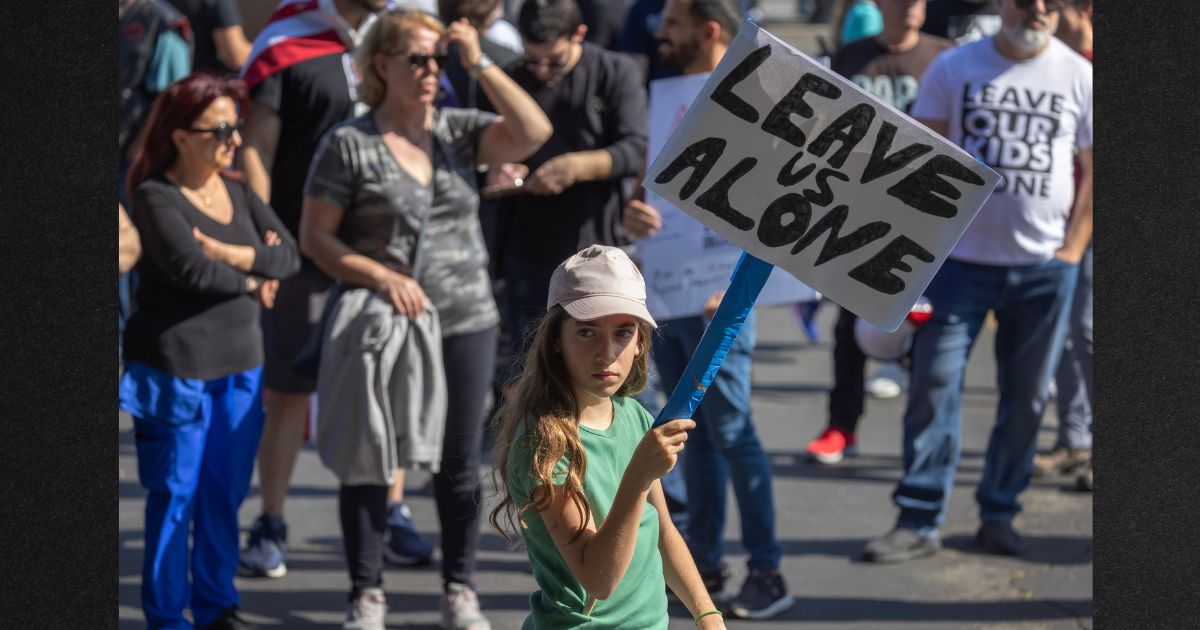 A girl holds a sign reading "Leave Us Alone" among anti-LGBTQ+ demonstrators outside a Glendale Unified School District Board of Education meeting in June of 2023 in Glendale, California.