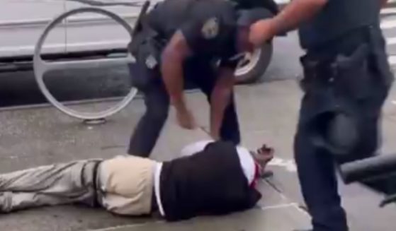 A New York police officer stands over a man that allegedly hit his partner, a female, as she was trying to break up a disturbance between the man and a group of kids.