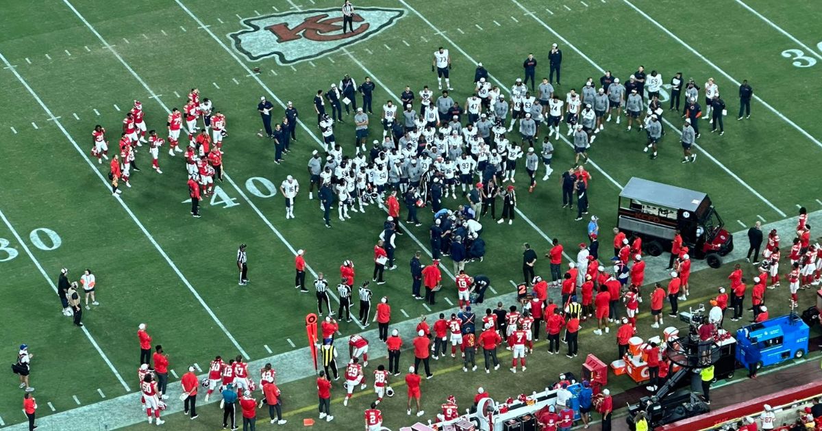 NFL players gather on the field as an injured player receives care.