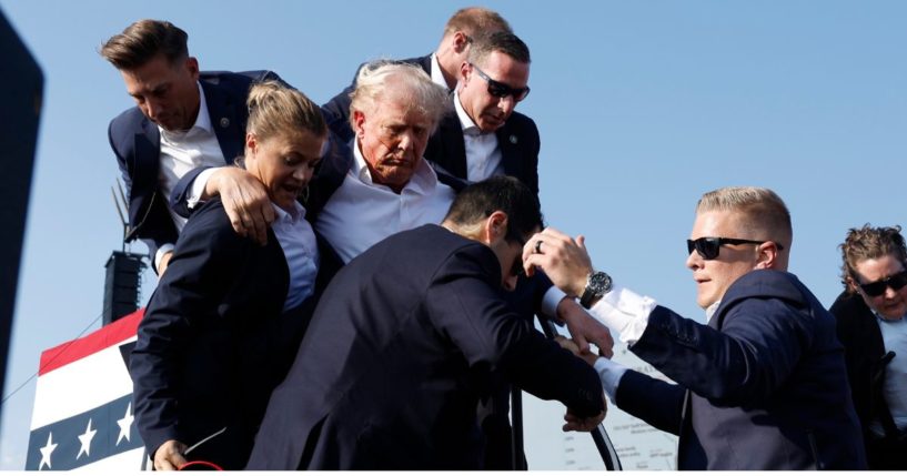 Former President Donald Trump, center, is surrounded by Secret Service agents after being shot by a would-be assassin at a campaign rally in Butler, Pennsylvania, on July 13.