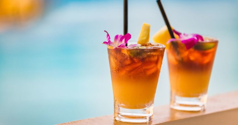 This stock image shows two drinks by a swimming pool at a hotel.