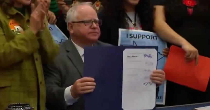 Minnesota Gov. Tim Walz holds up a bill he signed that will allow anyone in the state to receive their driver’s license, regardless of their immigration status.