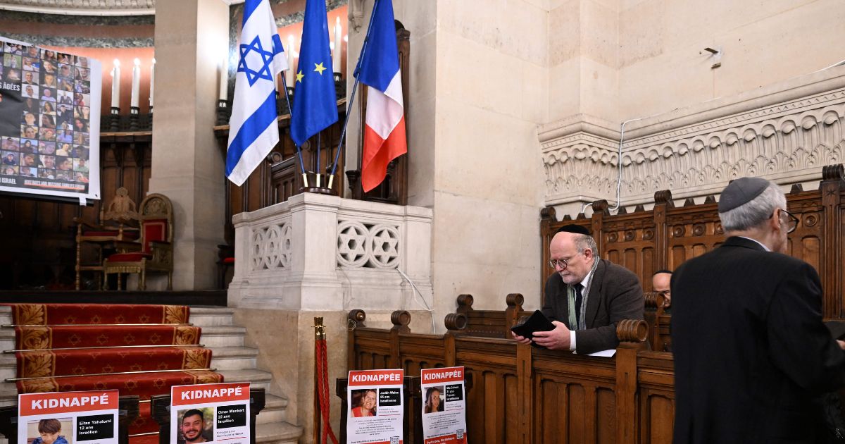 A member of the Jewish community prays next to portraits of hostages, abducted by Palestinian militants during the October 7 attack and currently held in the Gaza Strip, during an event held under the theme of "unity" and calling for their release, at the Great Synagogue of Paris, known as Synagogue de la Victoire, in Paris, on October 31, 2023.