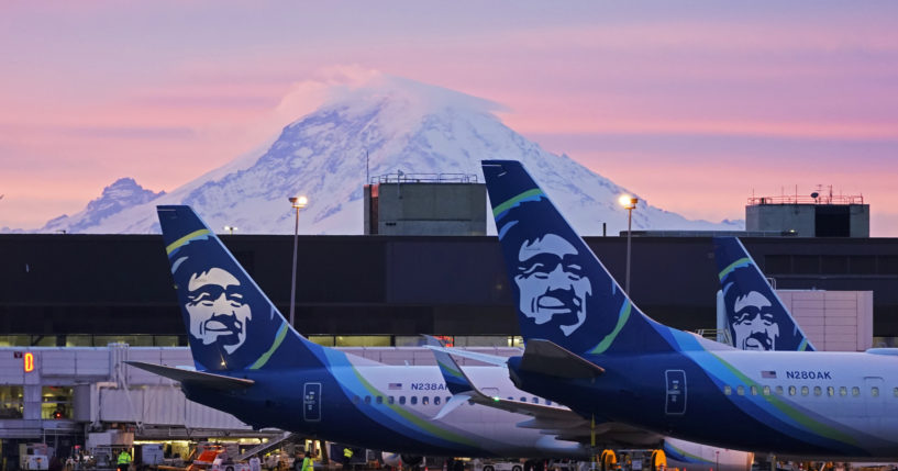 Alaska Airlines planes are shown parked at gates with Mount Rainier in the background at sunrise, March 1, 2021, at Seattle-Tacoma International Airport in Seattle.