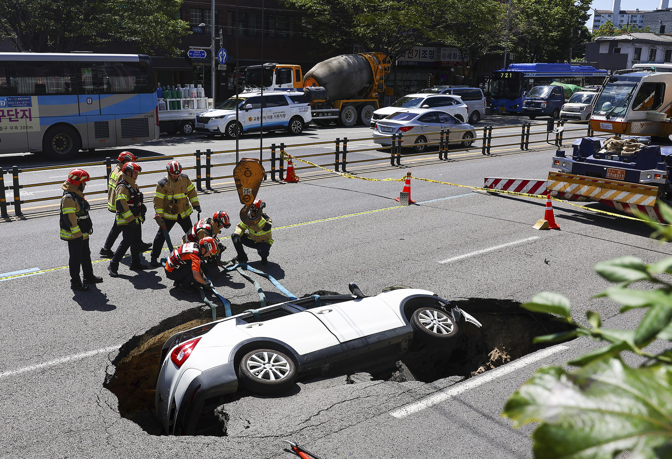 South Korean firefighters prepare to lift a vehicle that fell into a sinkhole on a street in Seoul, South Korea, Thursday, August 29, 2024.