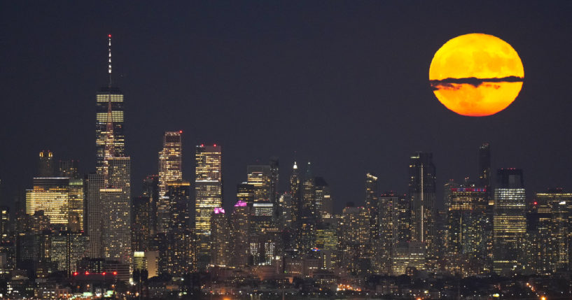 The moon rises through clouds over the skyline of lower Manhattan in this view from West Orange, New Jersey on Aug. 1, 2023, during a supermoon period.