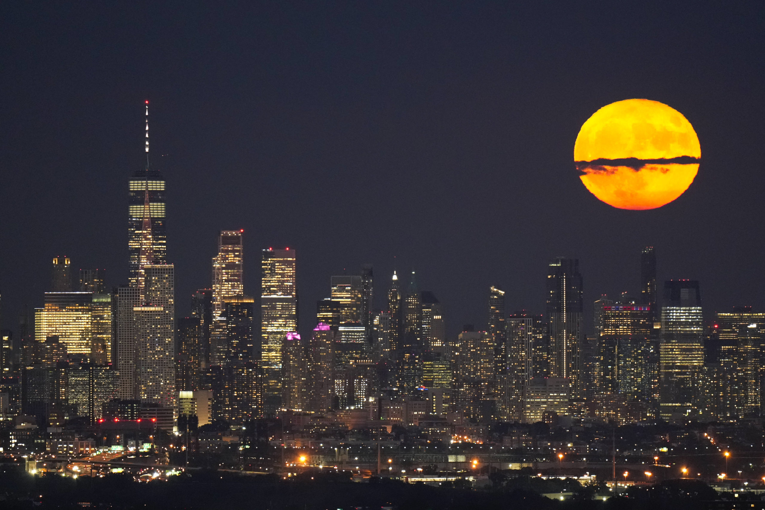 The moon rises through clouds over the skyline of lower Manhattan in this view from West Orange, New Jersey on Aug. 1, 2023, during a supermoon period.