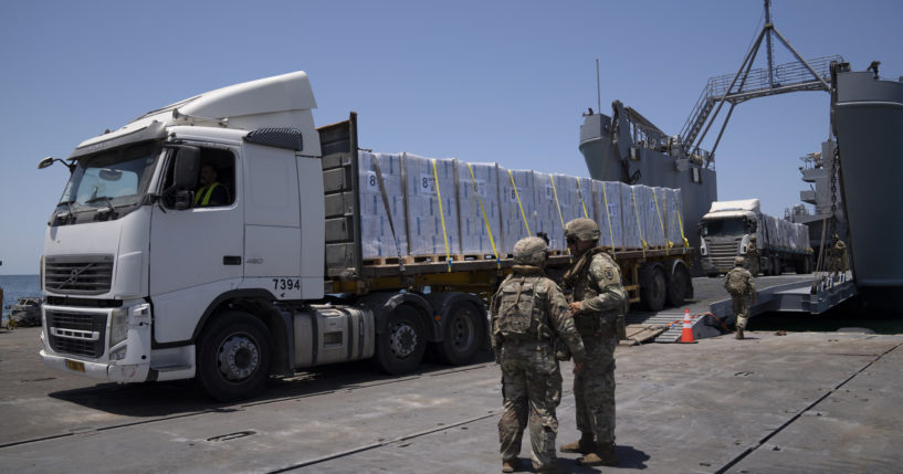 U.S. Army soldiers stand next to trucks arriving loaded with humanitarian aid at the U.S.-built floating pier Trident before reaching the beach on the coast of the Gaza Strip, June 25, 2024.