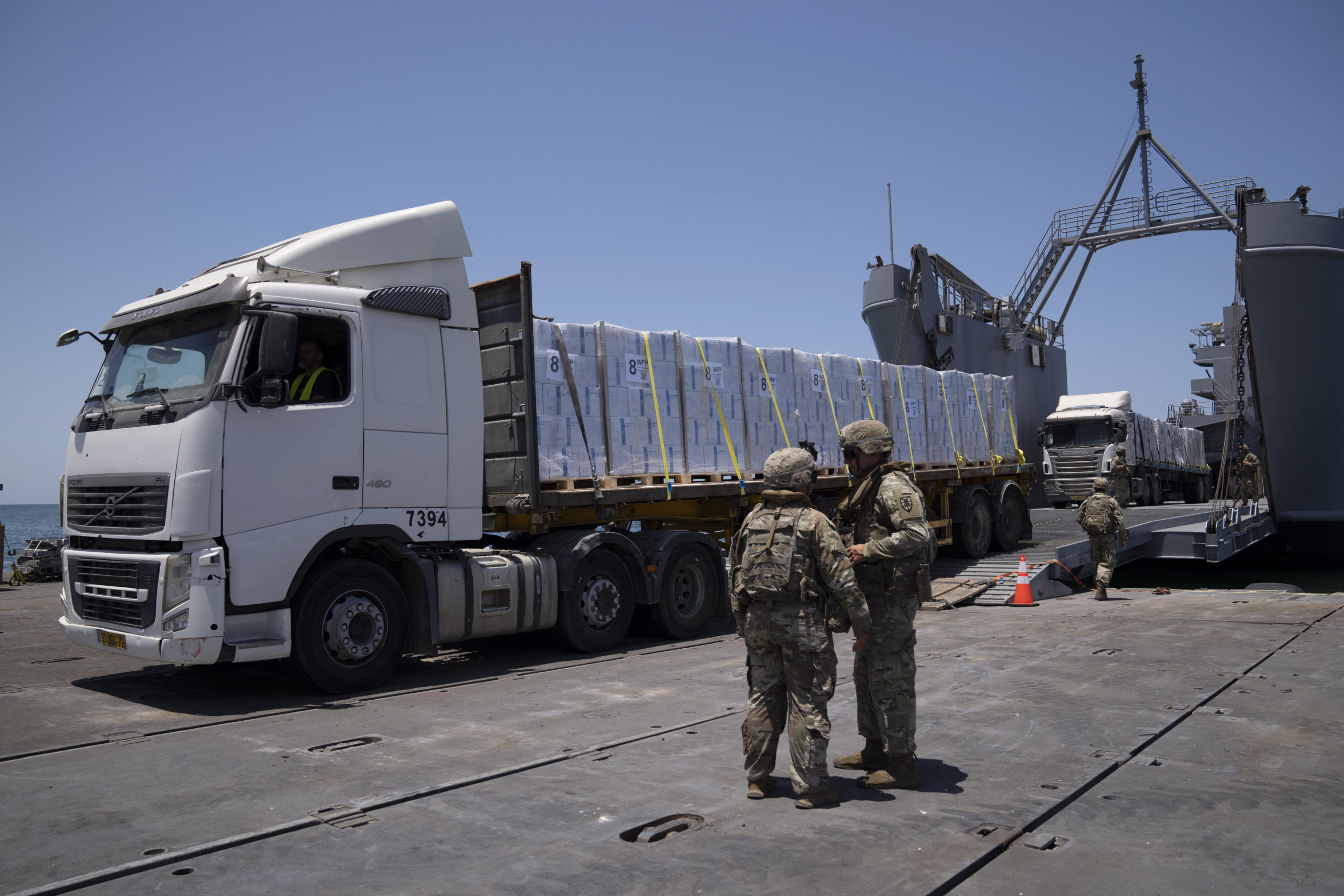 U.S. Army soldiers stand next to trucks arriving loaded with humanitarian aid at the U.S.-built floating pier Trident before reaching the beach on the coast of the Gaza Strip, June 25, 2024.