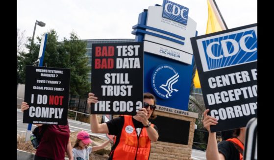 People hold signs at a protest against masks, vaccines, and vaccine passports outside the headquarters of the Centers for Disease Control (CDC) on March 13, 2021 in Atlanta, Georgia.