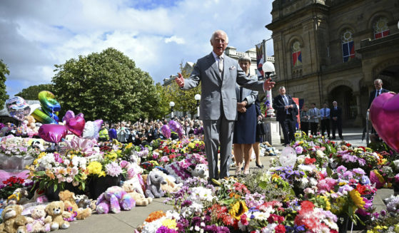 Britain's King Charles III looks at the tributes outside Southport Town Hall, in Southport, England, Tuesday, as he meets members of the local community, following the July 29 attack at a children's dance party.