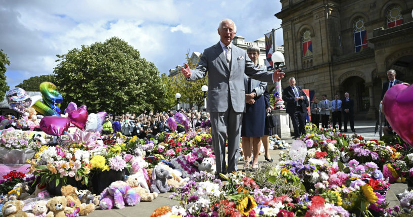 Britain's King Charles III looks at the tributes outside Southport Town Hall, in Southport, England, Tuesday, as he meets members of the local community, following the July 29 attack at a children's dance party.