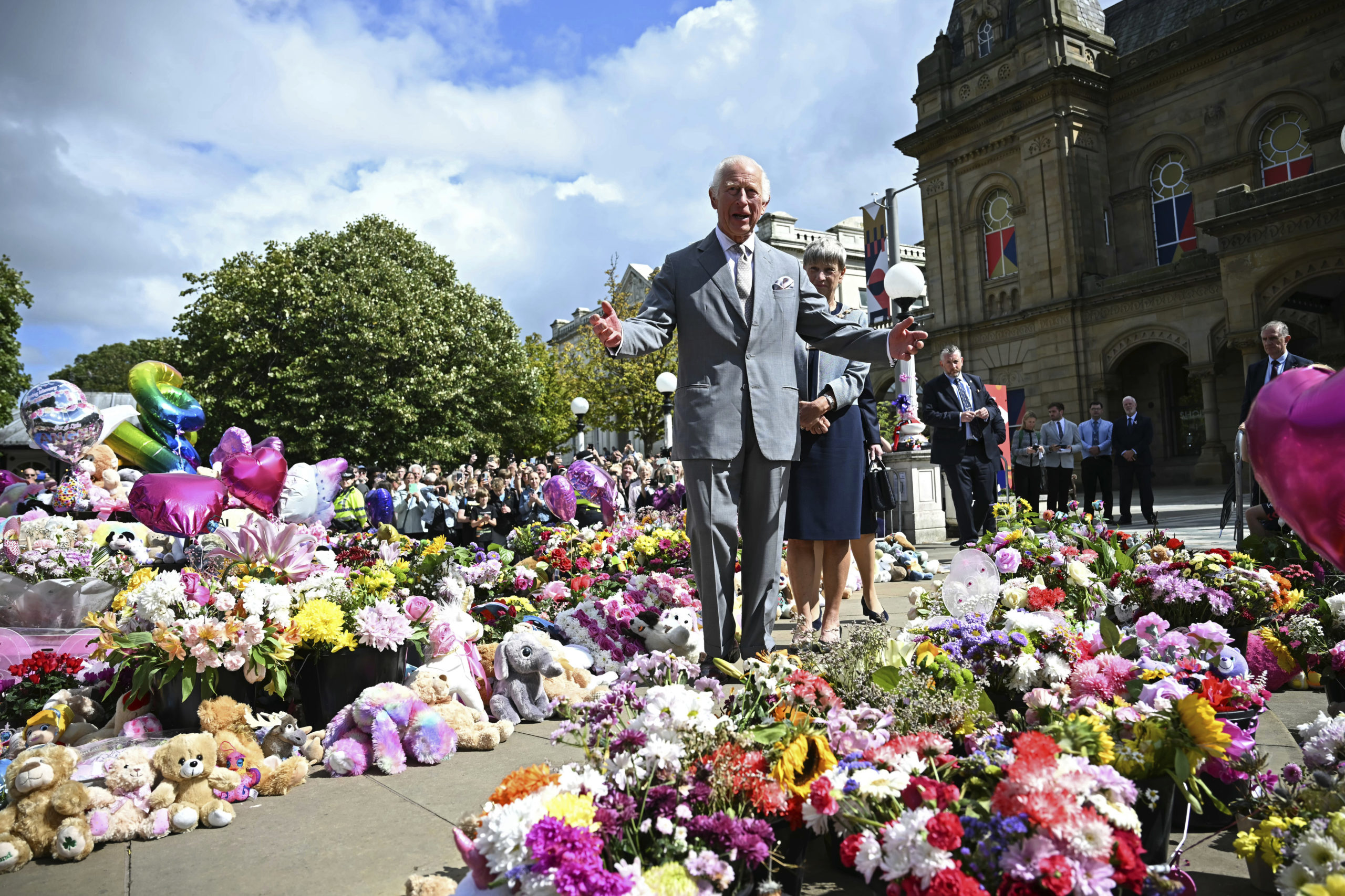 Britain's King Charles III looks at the tributes outside Southport Town Hall, in Southport, England, Tuesday, as he meets members of the local community, following the July 29 attack at a children's dance party.