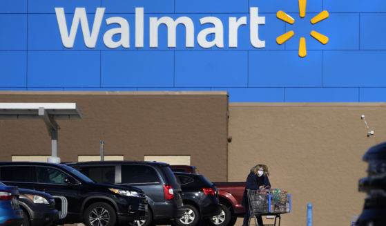 A woman wheels a cart with her purchases out of a Walmart store, November 18, 2020, in Derry, New Hampshire.