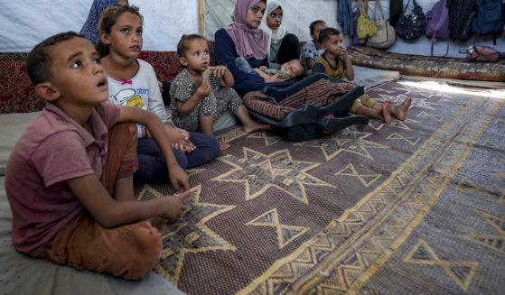 Displaced infant Abdel-Rahman Abu El-Jedian, 11-month-old, who suffers from polio, is carried by his mother, center, at a makeshift tent camp in Deir al-Balah, central Gaza Strip on Tuesday.