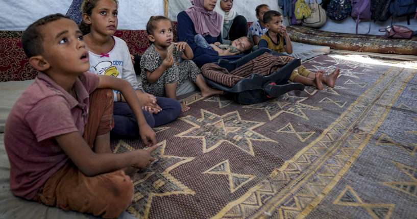 Displaced infant Abdel-Rahman Abu El-Jedian, 11-month-old, who suffers from polio, is carried by his mother, center, at a makeshift tent camp in Deir al-Balah, central Gaza Strip on Tuesday.