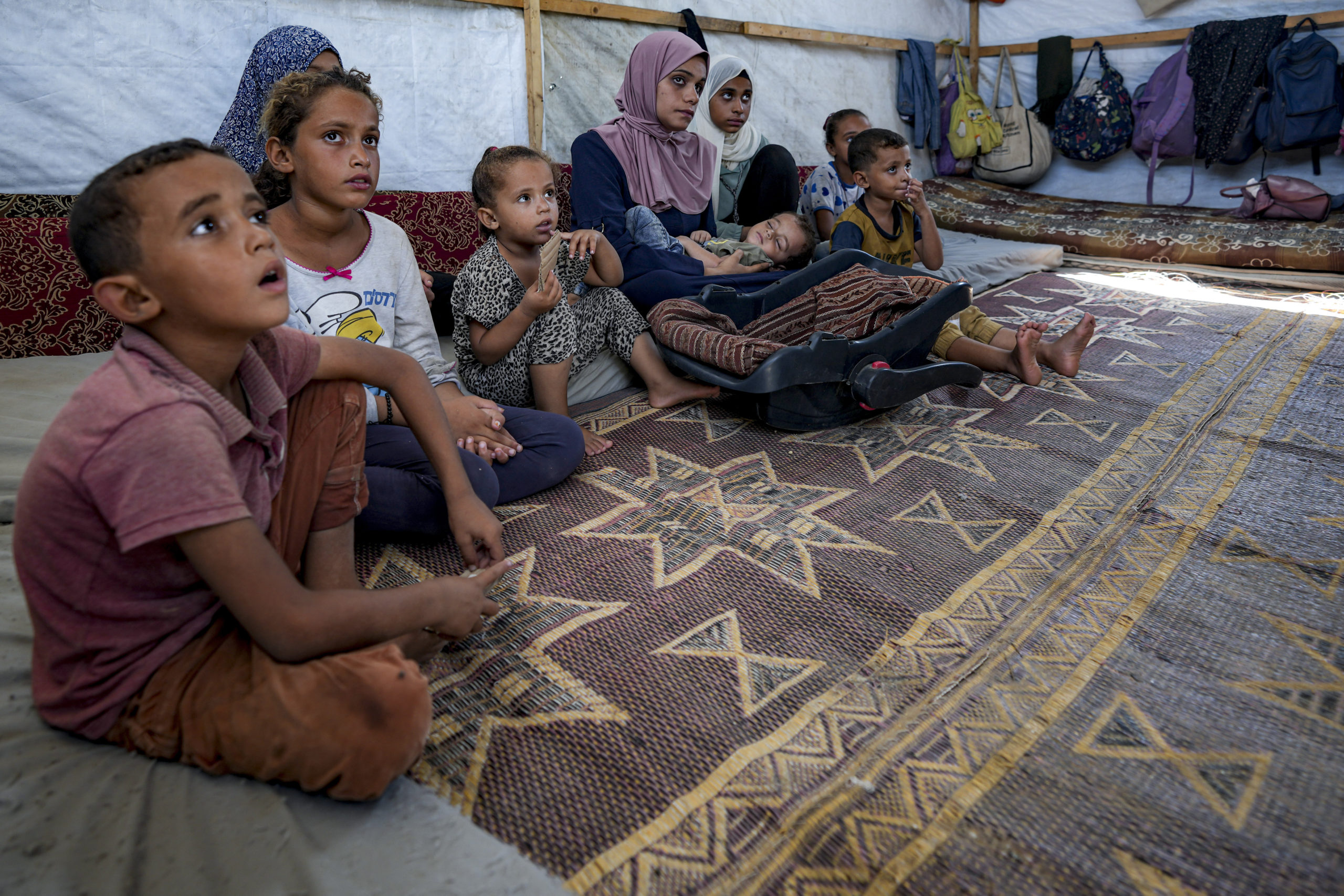 Displaced infant Abdel-Rahman Abu El-Jedian, 11-month-old, who suffers from polio, is carried by his mother, center, at a makeshift tent camp in Deir al-Balah, central Gaza Strip on Tuesday.