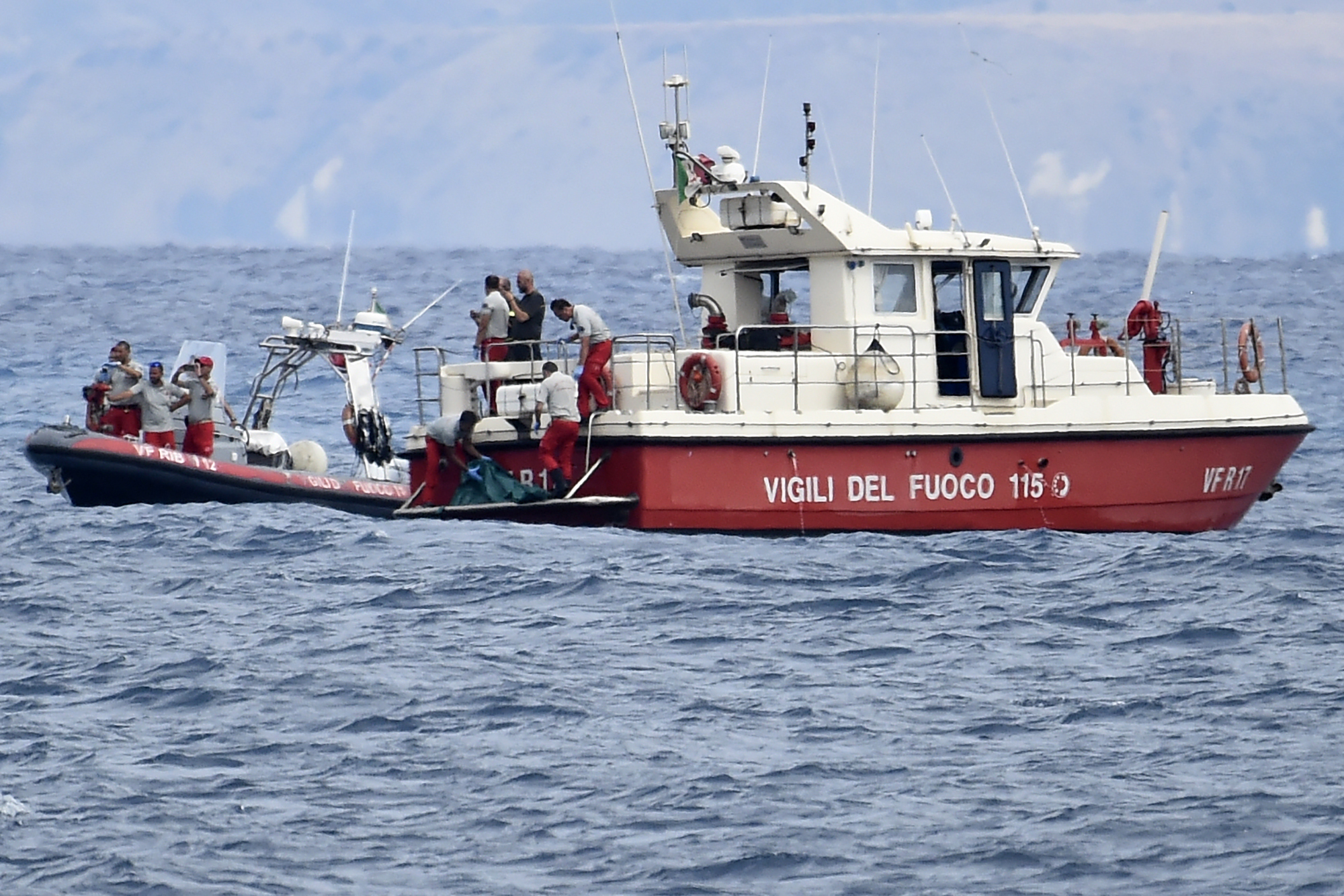 Italian Firefighter scuba divers bring ashore in a green bag the body of one of the victims of the UK flag vessel Bayesian on Wednesday. The sail yacht was hit by a violent sudden storm and sunk early Monday, while at anchor off the Sicilian village of Porticello near Palermo, in southern Italy.